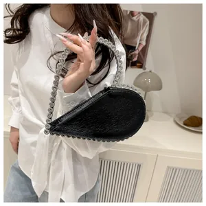 Detail einer schwarzen Herz-Handtasche mit kristallbesetztem Ringgriff für formelle Anlässe