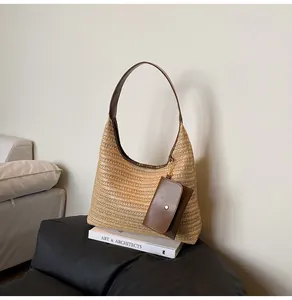 Detail of woven straw tote bag with brown leather straps and hanging coin purse accessory