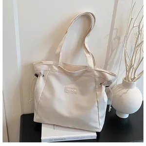 Détail du sac fourre-tout en toile crème avec cordon de serrage et écusson FASHION