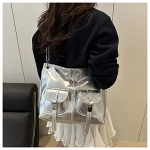 Detail of silver metallic tote bag featuring dual front pockets and glossy buckle hardware