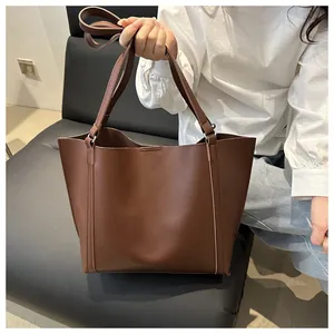 Detail view of the brown tote bag featuring vertical stitching and soft matte PU texture
