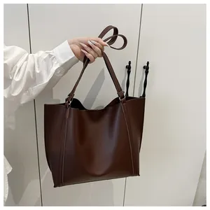 Close-up of a large dark brown matte leather tote bag with long shoulder straps