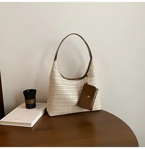 Detail of a straw tote bag with brown leather strap and small detachable card pouch