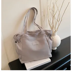 Détail du sac cabas lilas avec étiquette de mode sur un livre blanc et décor de branche