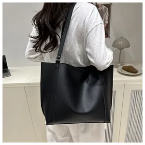 Close-up of a large black vintage tote bag with decorative stitching on a shoulder model