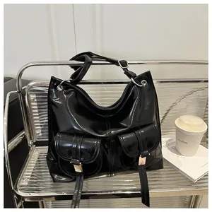 Detail of black patent leather tote bag with silver buckles and retro utility pockets