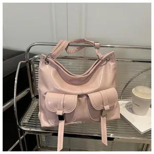 Detail of pink patent leather tote bag with symmetrical flap pockets and silver buckles