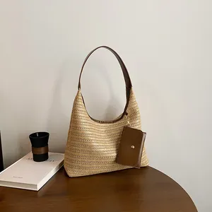 Large woven straw tote bag with brown leather shoulder strap and small detachable pouch