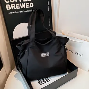 Sac fourre-tout noir en toile avec cordon de serrage et logo métallique dans un coffret