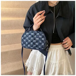 Close-up of a blue denim checkered handbag with leather straps worn by a model