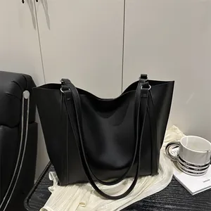 Minimalist black oversized tote bag with silver rings on elegant white fabric background