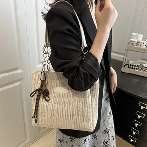 Chic cream straw tote bag with V-weave pattern and leather strap on model shoulder