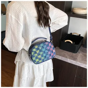 Detail of colorful plaid fringe crossbody bag worn with a white textured maxi dress