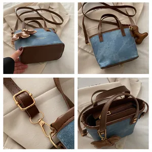 Detailansicht der blauen Denim-Beuteltasche mit braunen Lederriemen und Goldbeschlägen