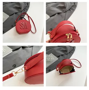 Detail view of red round crossbody bag with gold hardware and SM letter decor
