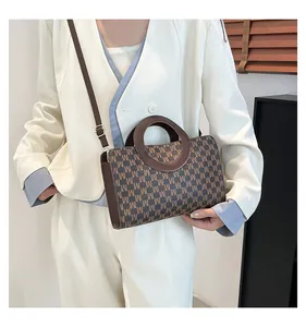 Detail of a brown M-pattern crossbody bag with unique circular handles and texture