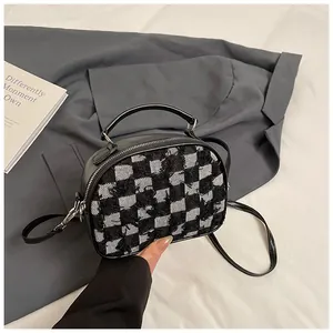 Detail of black and white checkerboard tweed fabric and leather strap on the handbag