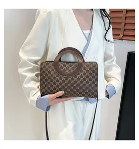 Close-up of a retro patterned square bag with a unique round handle on white suit