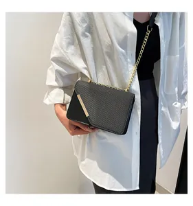 Close-up of black crossbody bag with diagonal texture and gold chain strap