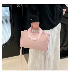 Detail of pink small square bag featuring circular handle and subtle monogram texture