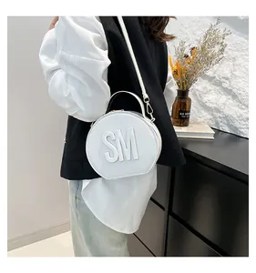 Chic white circular bag with 3D SM letters worn by a model in a minimalist setting