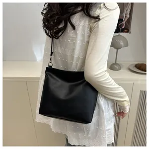 Vue détaillée du grand sac cabas noir montrant la texture et la bandoulière portée