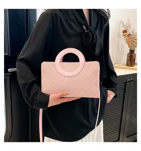 Close-up of pink leather handbag featuring embossed M patterns and round handle