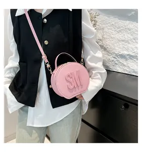 Detail of round pale pink crossbody bag with embossed SM letters and golden zippers