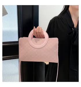 Detail of light pink crossbody bag with M-letter print and unique circular handle design