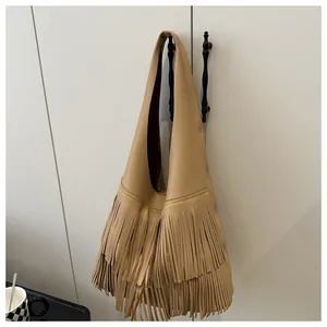 Detailed macro view of bohemian leather fringe bag with rich litchi grain texture