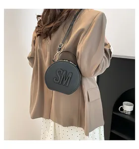 Close-up of black saddle bag with 3D letter embossing and detachable shoulder strap