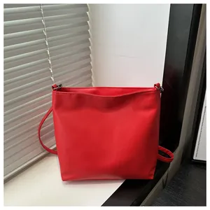 Gros plan d'un sac cabas rouge vif posé sur le rebord d'une fenêtre blanche