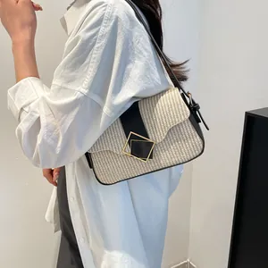 Chic woven shoulder bag in beige and black with a gold geometric buckle on a model
