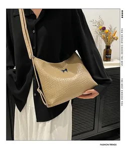 Détail du sac à bandoulière marron clair tressé avec boucle en métal en forme de papillon