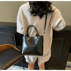 Vue arrière d'un sac seau noir brillant avec doubles poignées et une bandoulière amovible