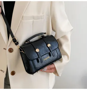 Detail of black leather handbag with gold buckles and adjustable shoulder strap