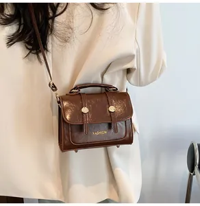Close-up of vintage dark brown crossbody bag with glossy texture and gold fashion logo