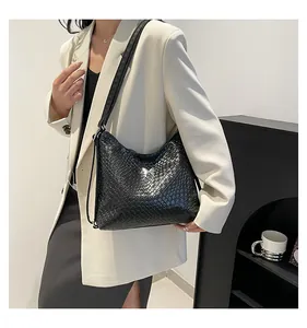 Détail d'un sac à bandoulière noir tressé avec boucle métallique en forme de papillon argenté