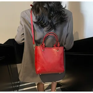 Détail du sac cabas rouge brillant montrant les nœuds de poignée et le fini lisse