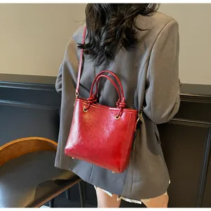 Détail d'un sac seau vintage rouge foncé en cuir brillant porté par un mannequin