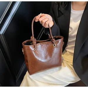 Gros plan d'un sac à main marron foncé vintage avec poignée nouée et anneaux dorés