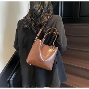 Détail du sac seau marron vintage montrant la texture du cuir et les clous métalliques dorés