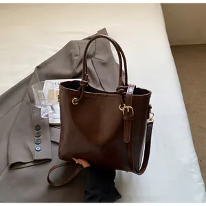 Détail d'un sac cabas marron foncé vintage avec texture cuir brillant et garnitures dorées