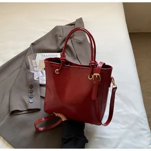 Détail du sac à main rouge avec poignée nouée et ferrures dorées sur décor chic