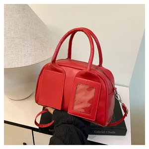 Detailansicht einer hellroten Boston-Tasche mit glatter Textur und Silberbeschlägen