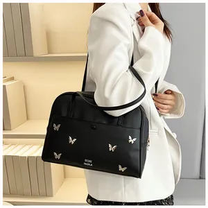 Détail du cabas en cuir noir avec papillons argentés et lettrage de la marque