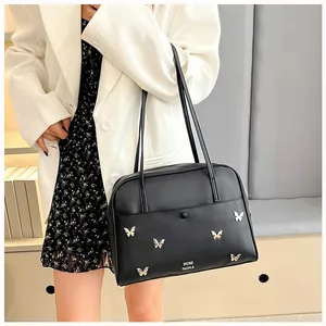 Vue détaillée du sac cabas noir avec breloques papillons dorés et fines bandoulières