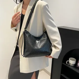 Sac bandoulière tressé noir pour femme avec détail papillon argenté sur blazer beige