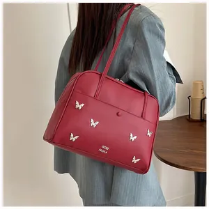 Détail du cabas rouge avec papillons argentés et lettrage de marque porté par un mannequin