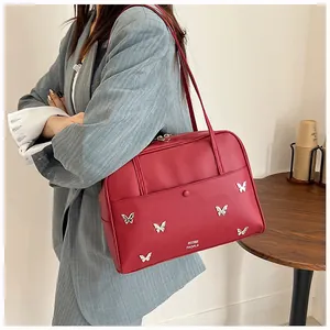 Détail du sac cabas rouge avec papillons argentés porté sur un blazer gris